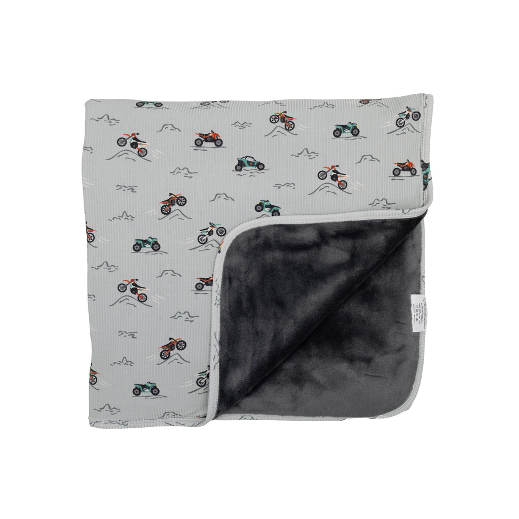 Blanket with motorcycle pattern on one side and solid color on the other, on a white background