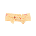Yellow headband with a bow and pink heart designs on a white background