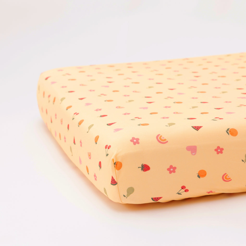 Yellow fruity-patterned fitted sheet on a white background