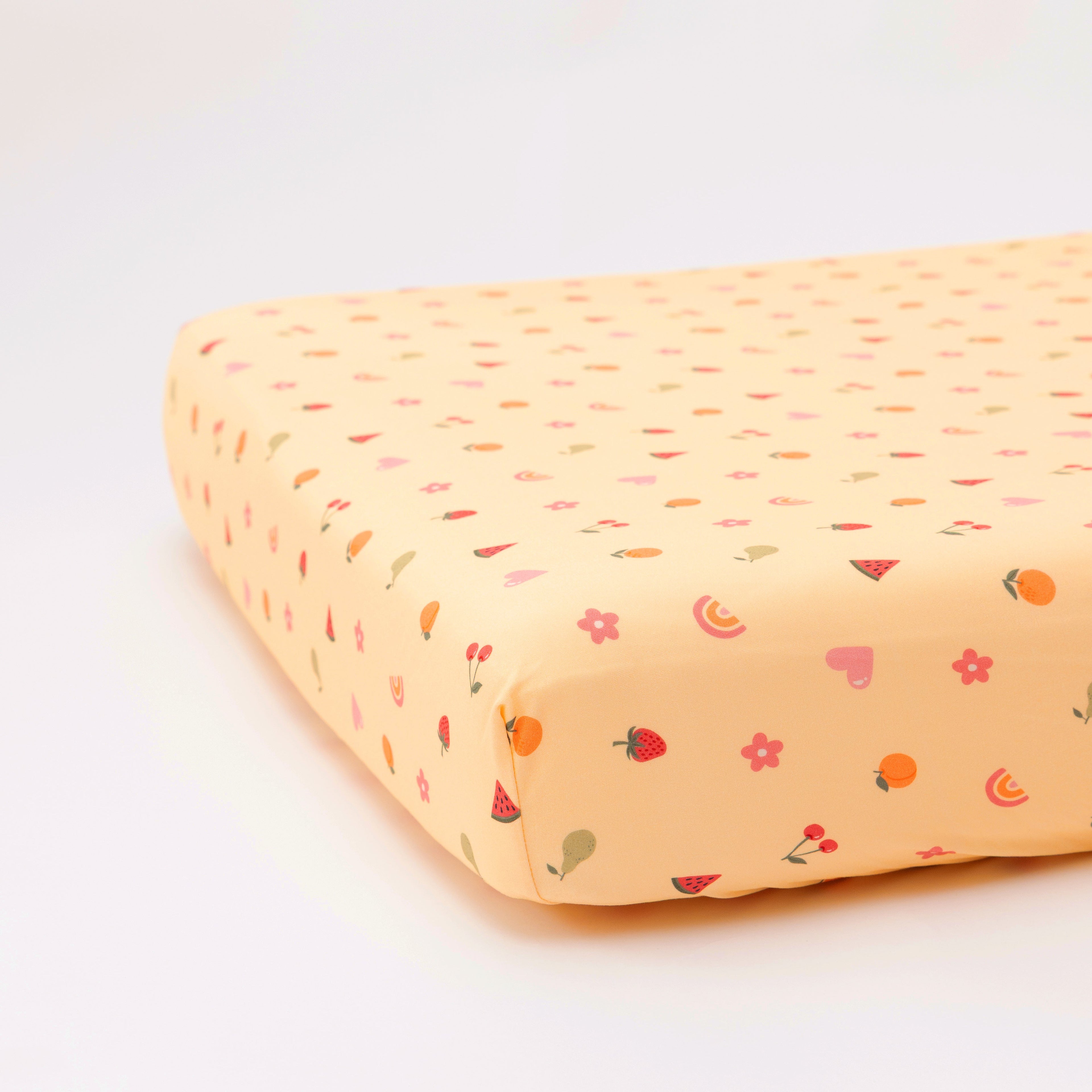 Yellow fruity-patterned fitted sheet on a white background