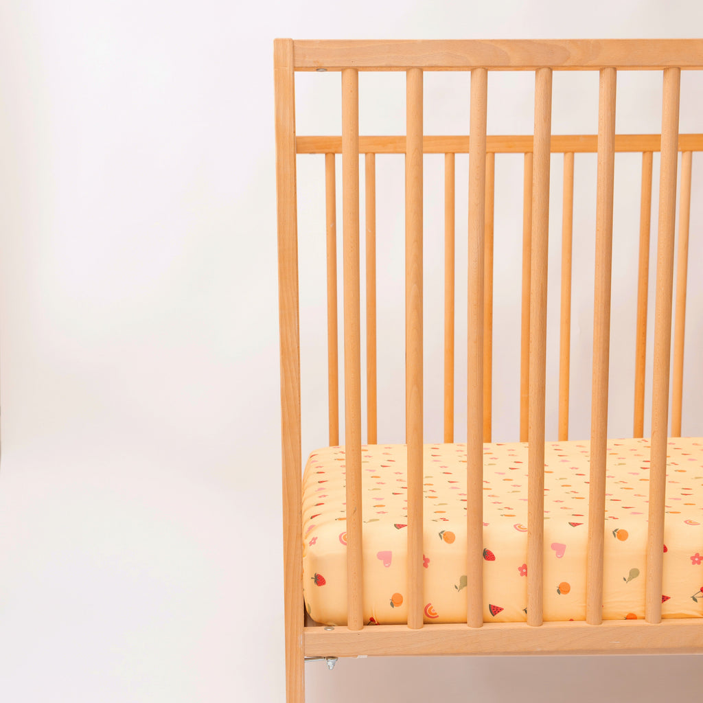 Wooden crib with a patterned mattress on a white background
