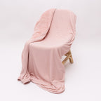 Pink striped blanket draped over a chair on a white background