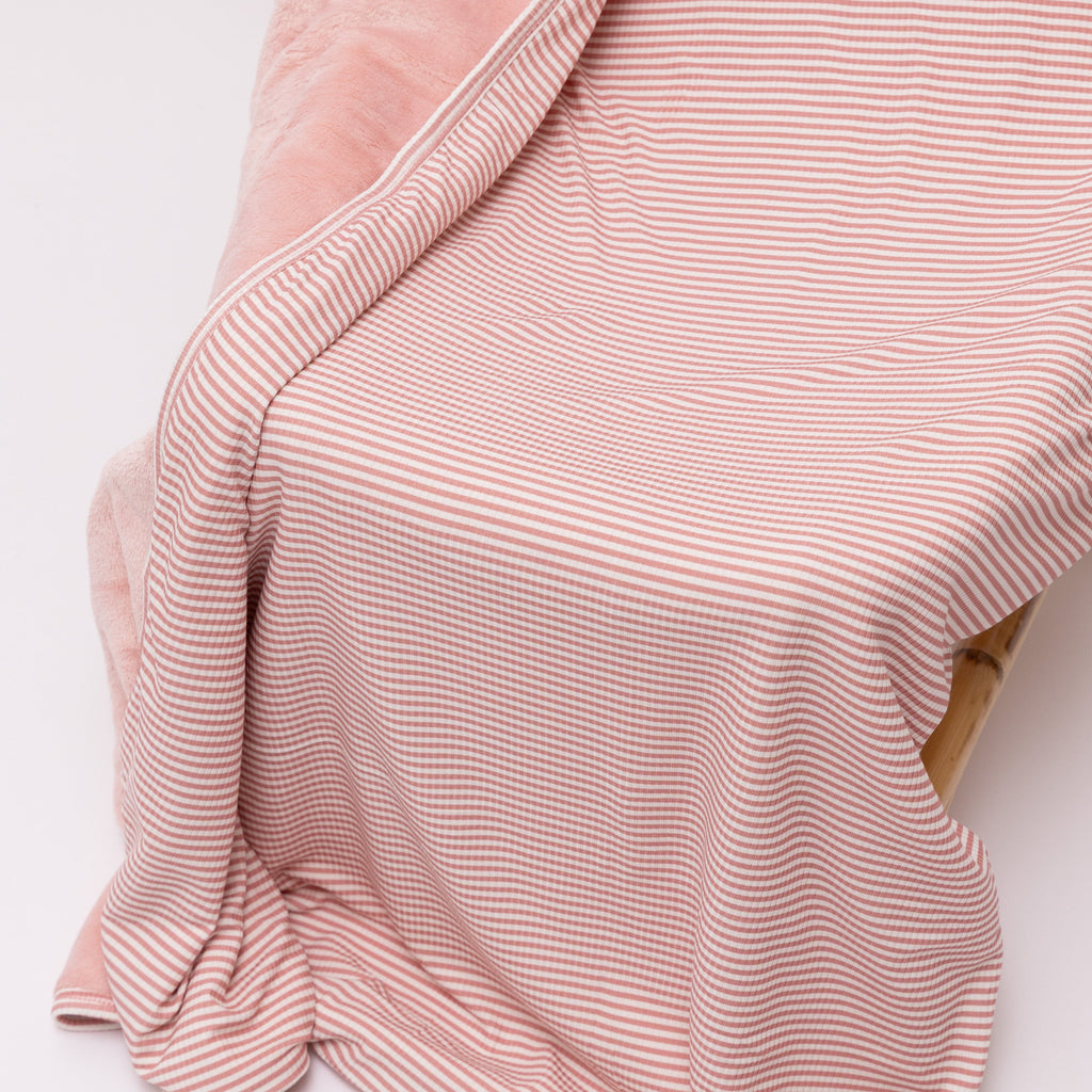 Pink striped blanket draped over a chair on a white background