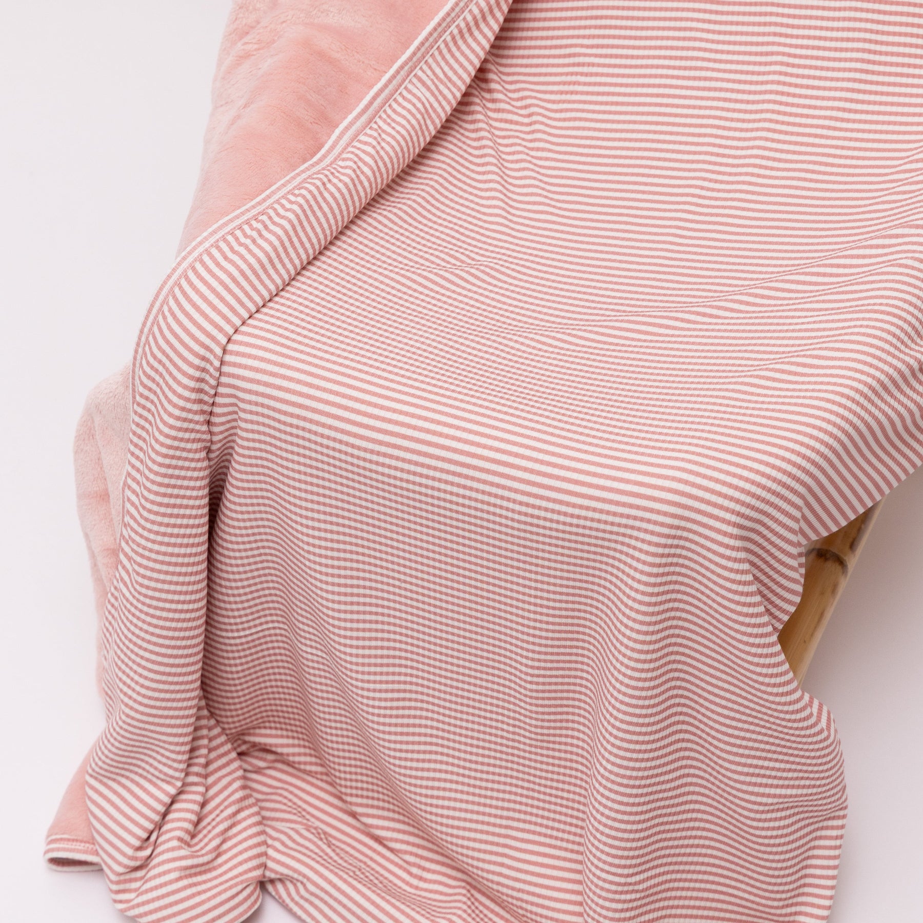Pink striped blanket draped over a chair on a white background