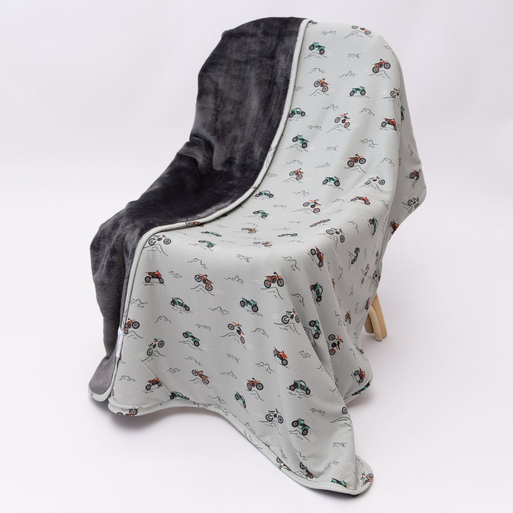 Blanket with off-road vehicle pattern draped over a chair on a white background