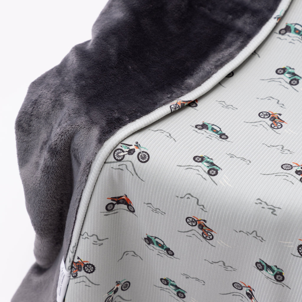 Close up shot of a blanket with off-road vehicle pattern draped over a chair on a white background