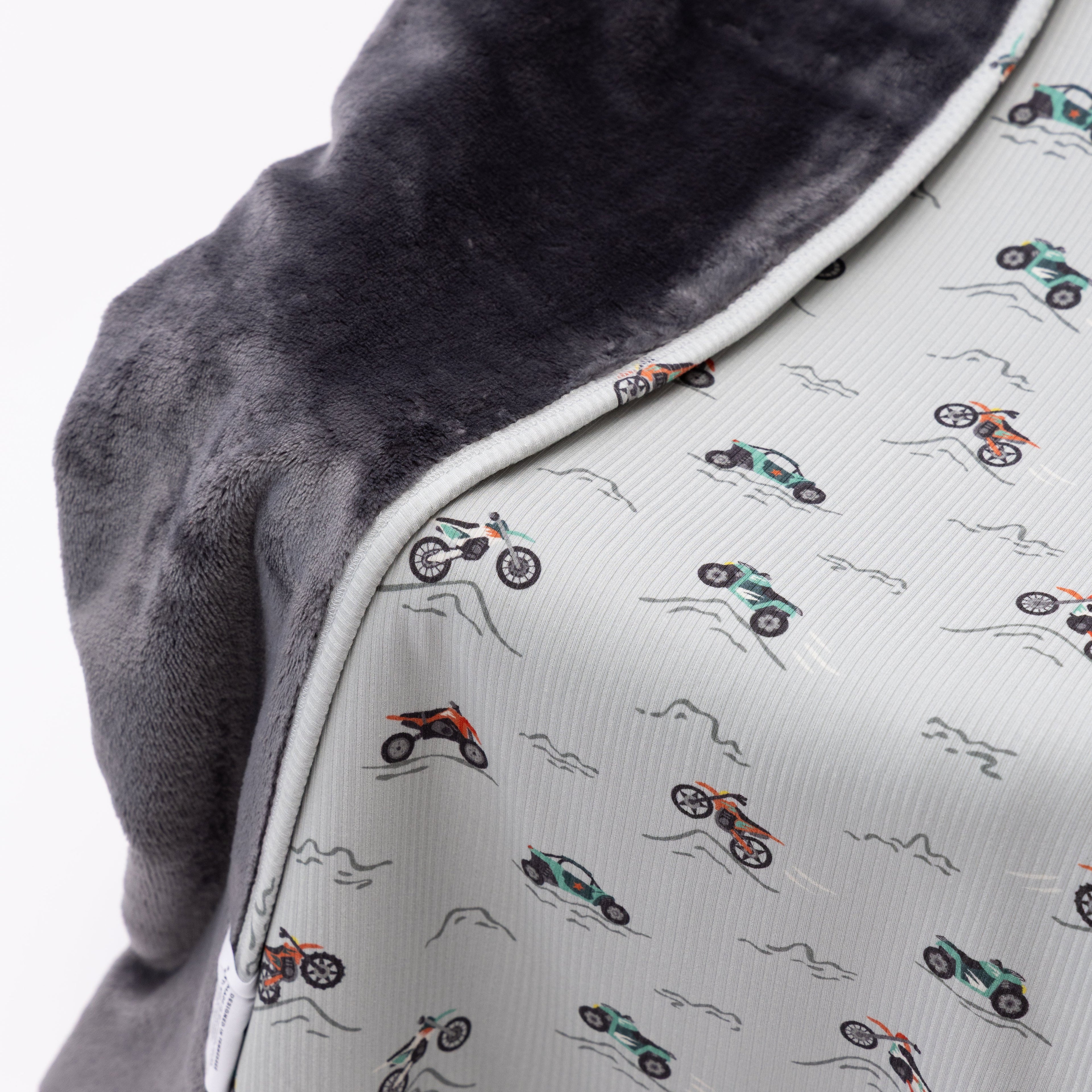 Close up shot of a blanket with off-road vehicle pattern draped over a chair on a white background