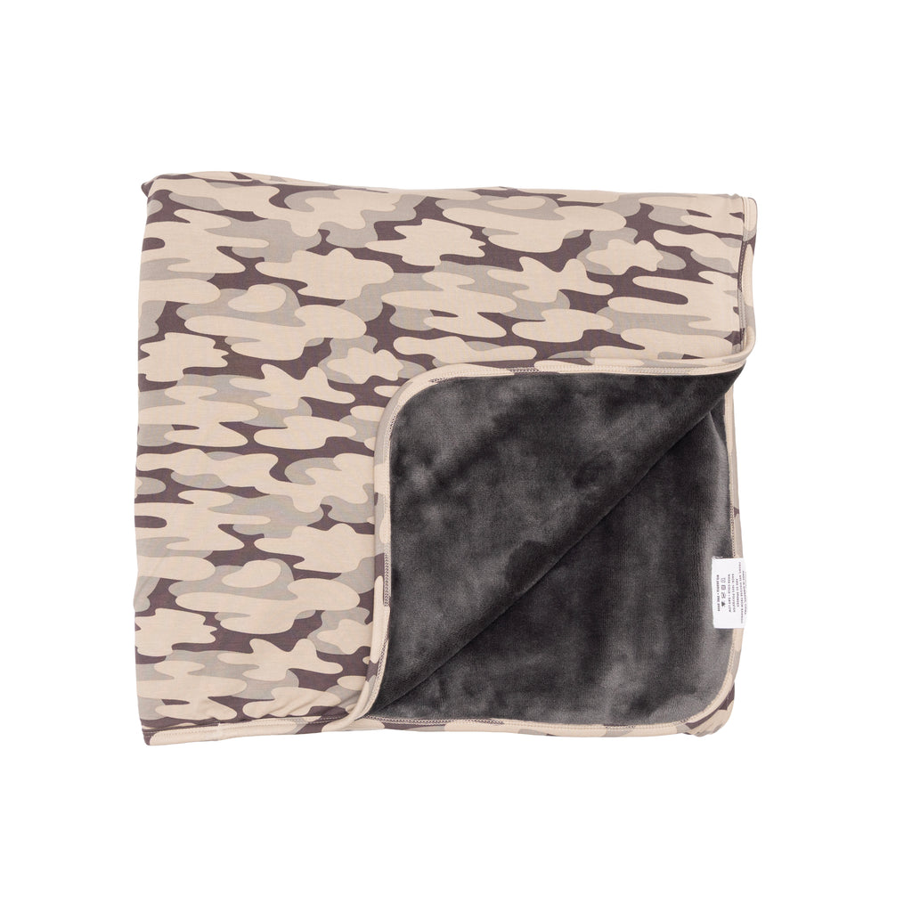 Camouflage-patterned blanket with dark backing on a white background