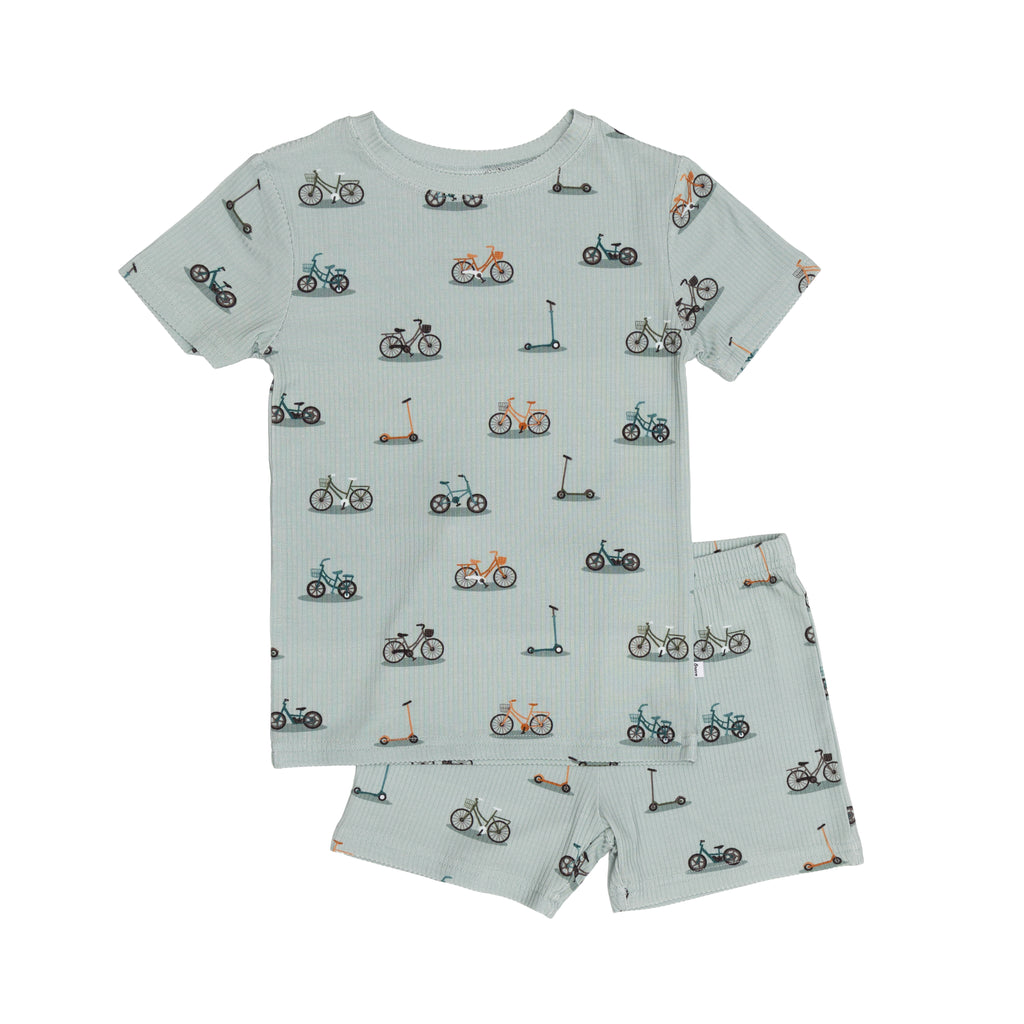 Children's pajama shorts set with bike and scooter pattern on a light blue background