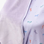 Close up shot of a light purple baby blanket with colorful unicorn patterns on a white background