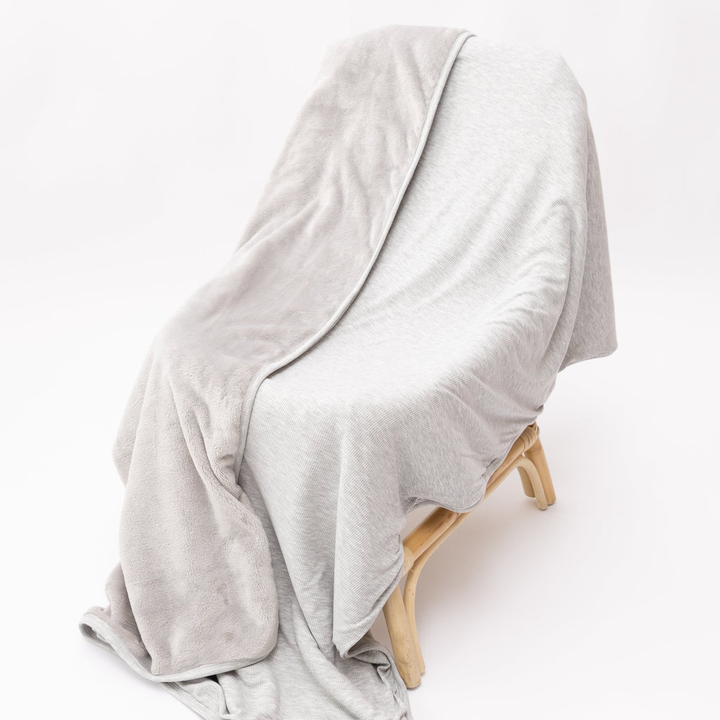 Gray blanket draped over a wooden chair on a white background