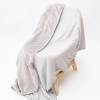 Gray blanket draped over a wooden chair on a white background