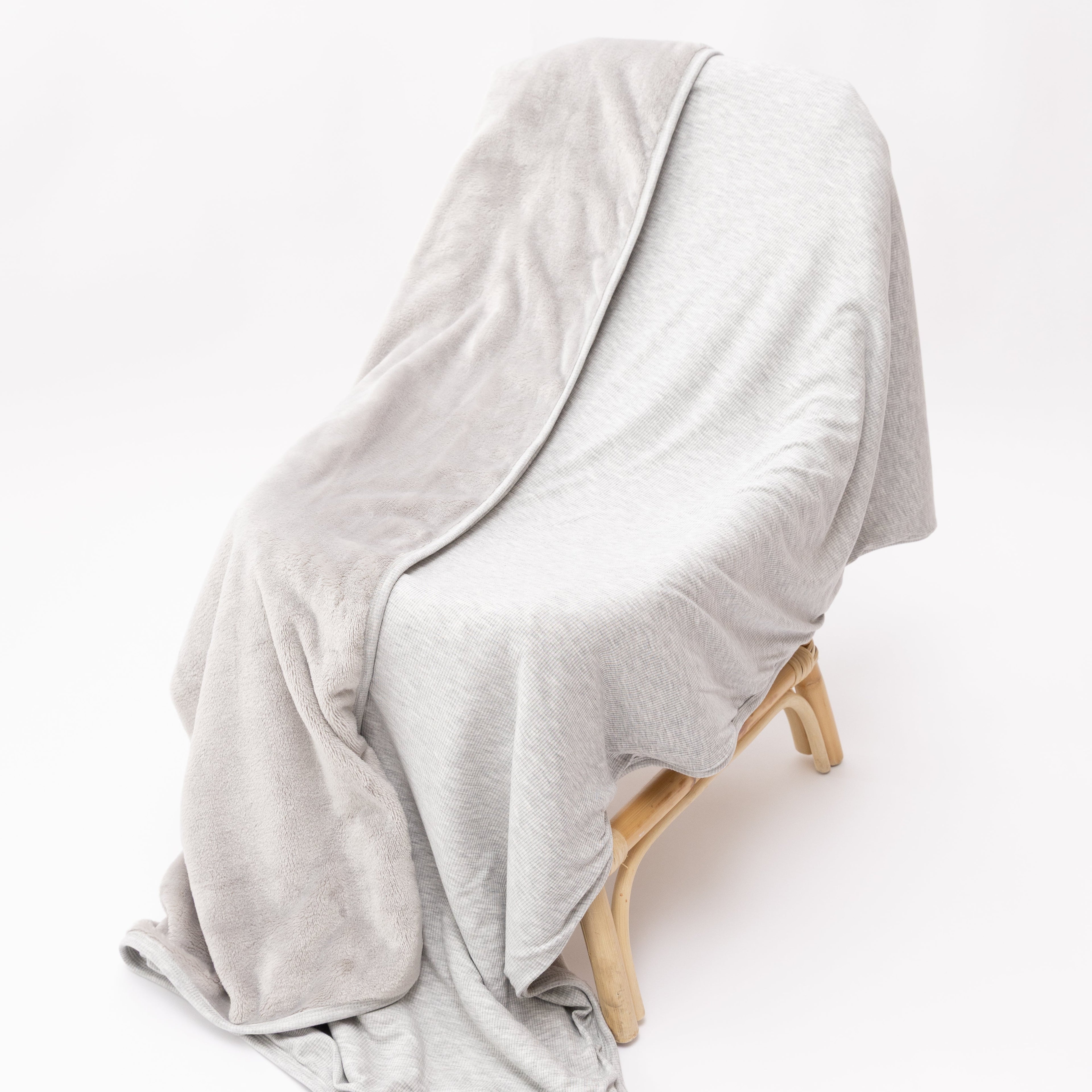 Gray blanket draped over a wooden chair on a white background
