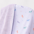 Close up shot of a light purple baby blanket with colorful unicorn patterns on a white background