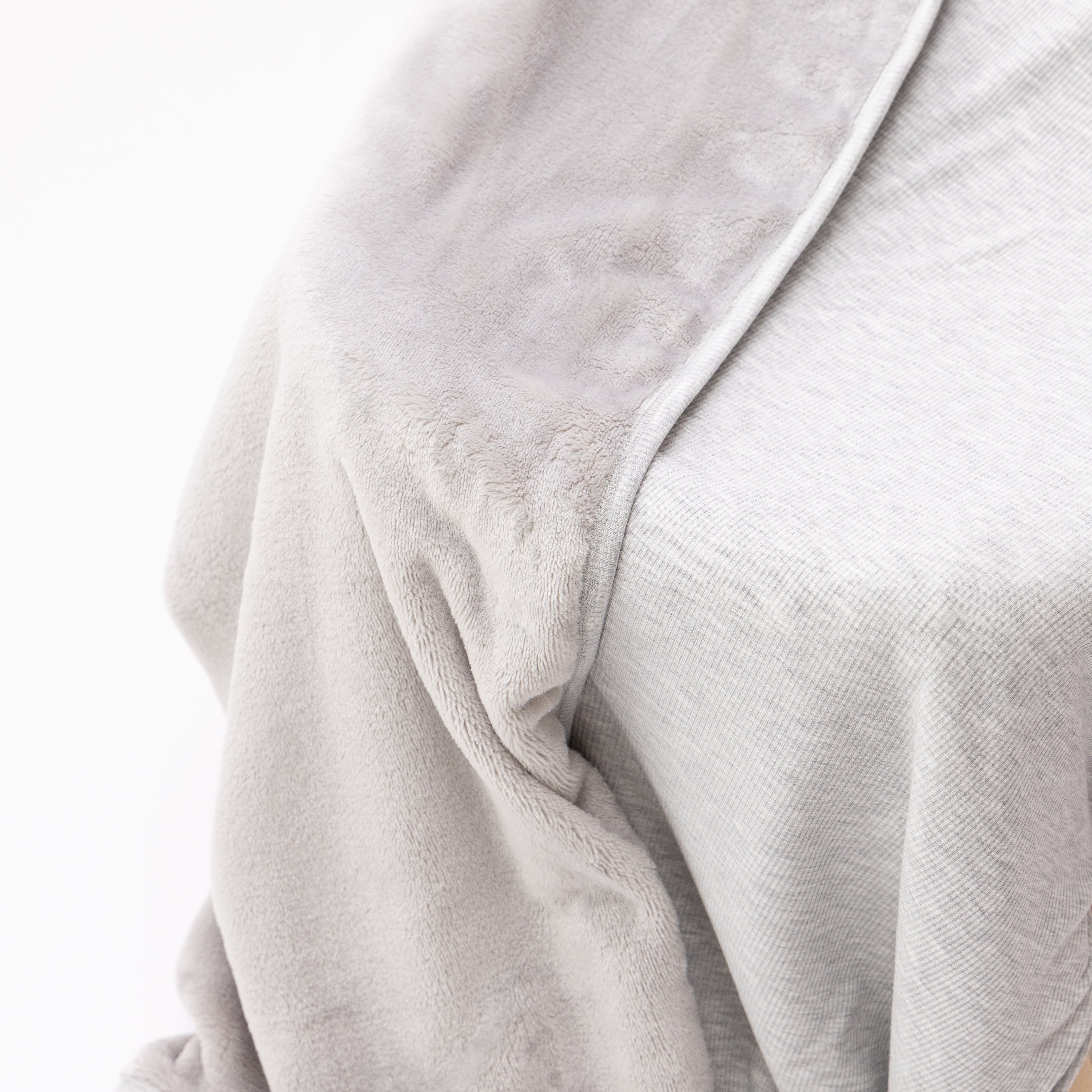 Close up of a gray blanket draped over a wooden chair on a white background