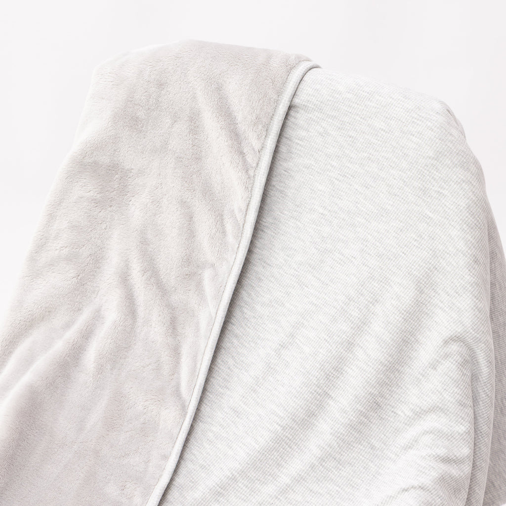 Close up of a gray blanket draped over a wooden chair on a white background