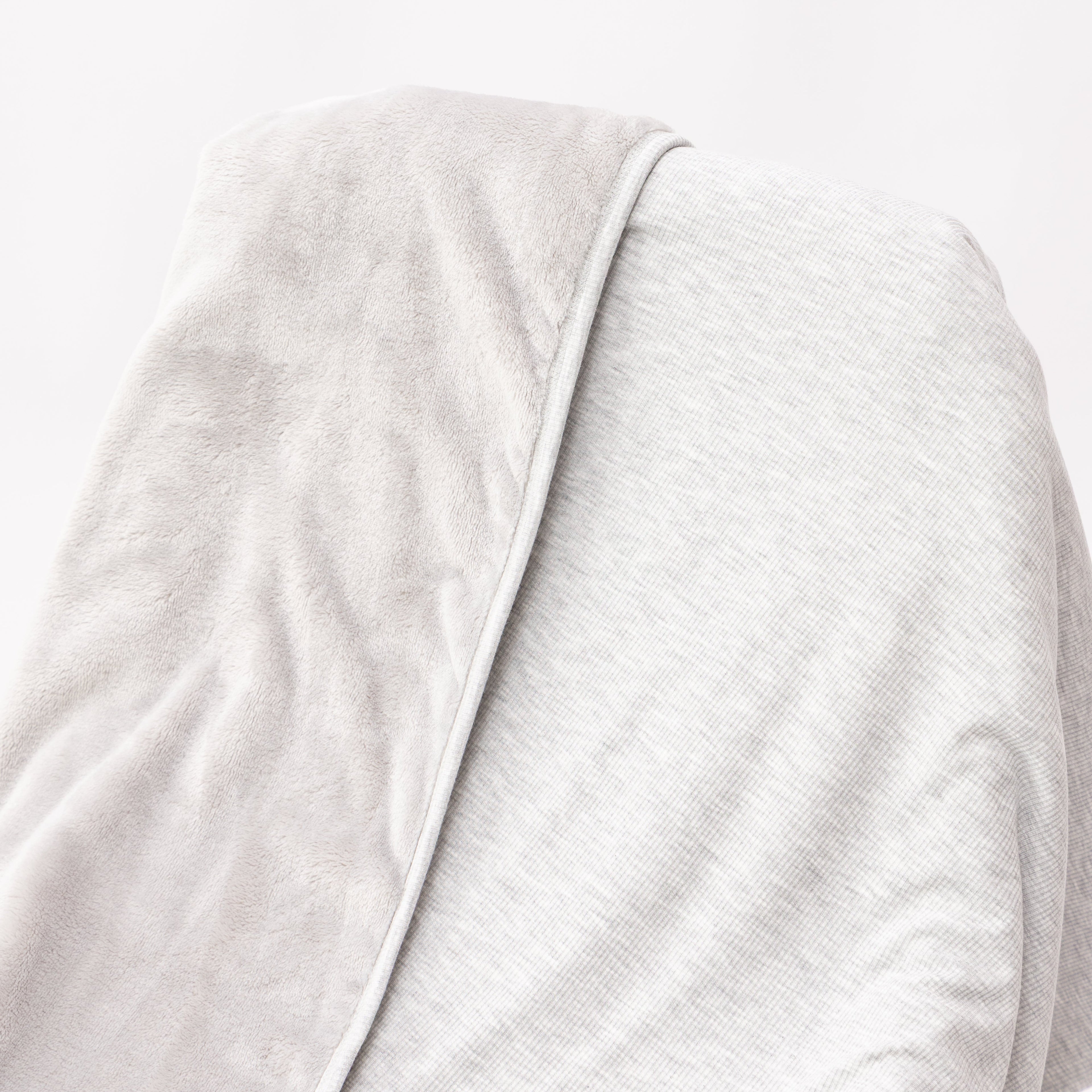 Close up of a gray blanket draped over a wooden chair on a white background
