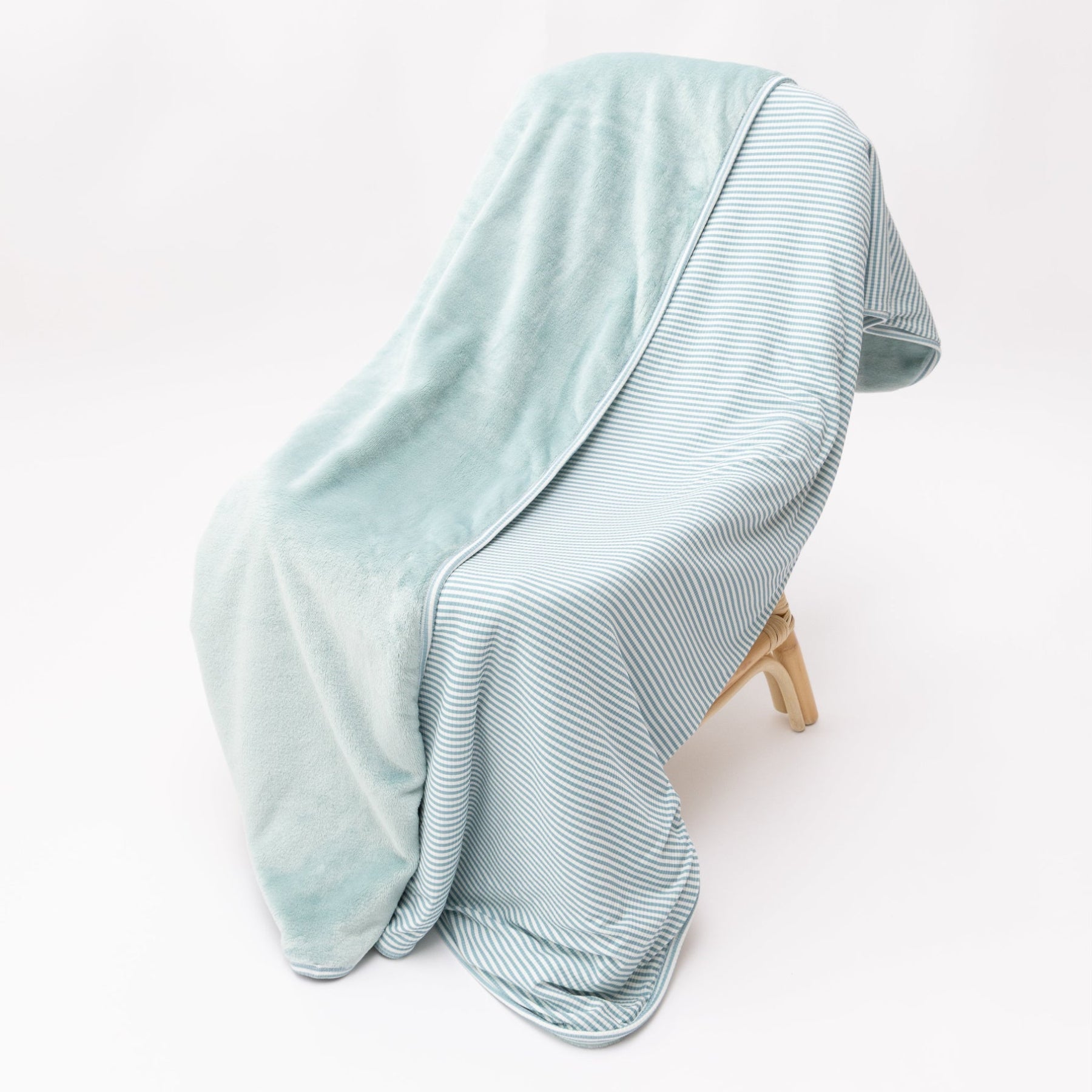 Light blue striped blanket draped over a wooden chair on a white background
