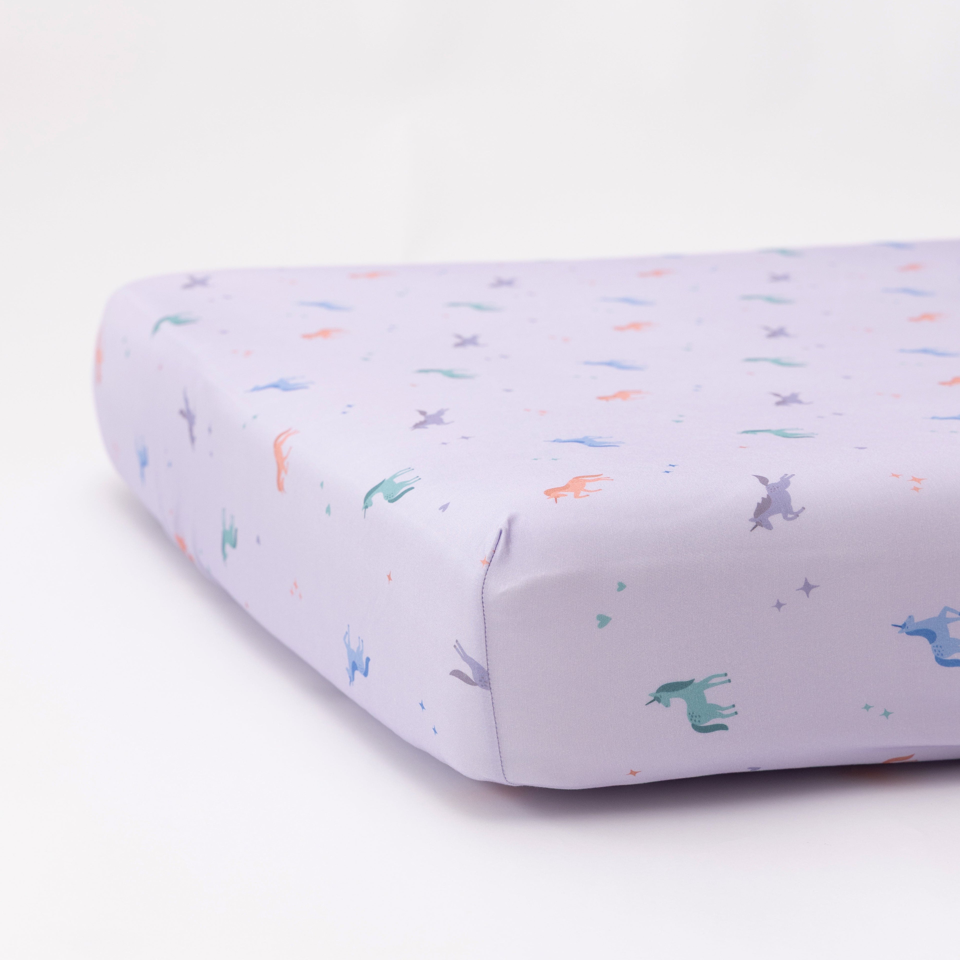 Fitted crib sheet with colorful unicorn patterns on a white background