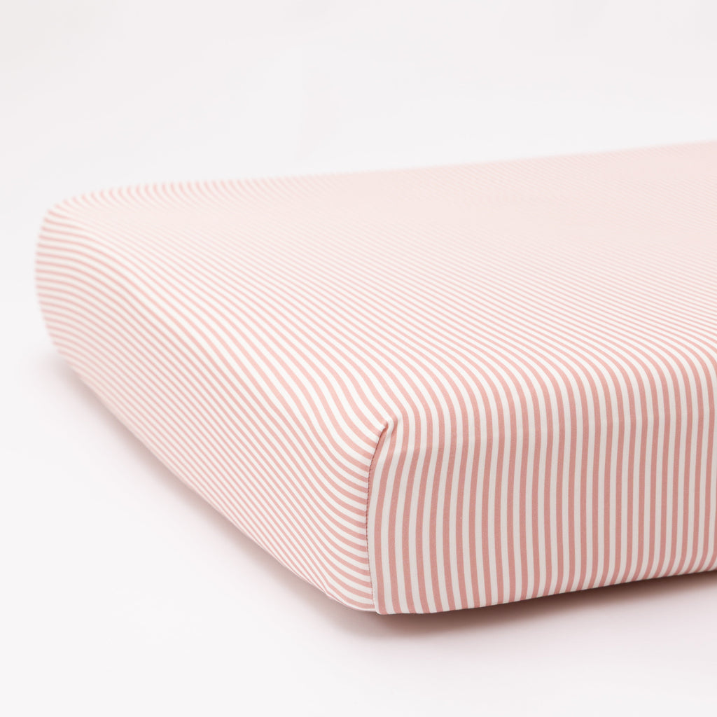 Pink and white striped crib sheet on a white background