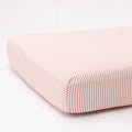 Pink and white striped crib sheet on a white background
