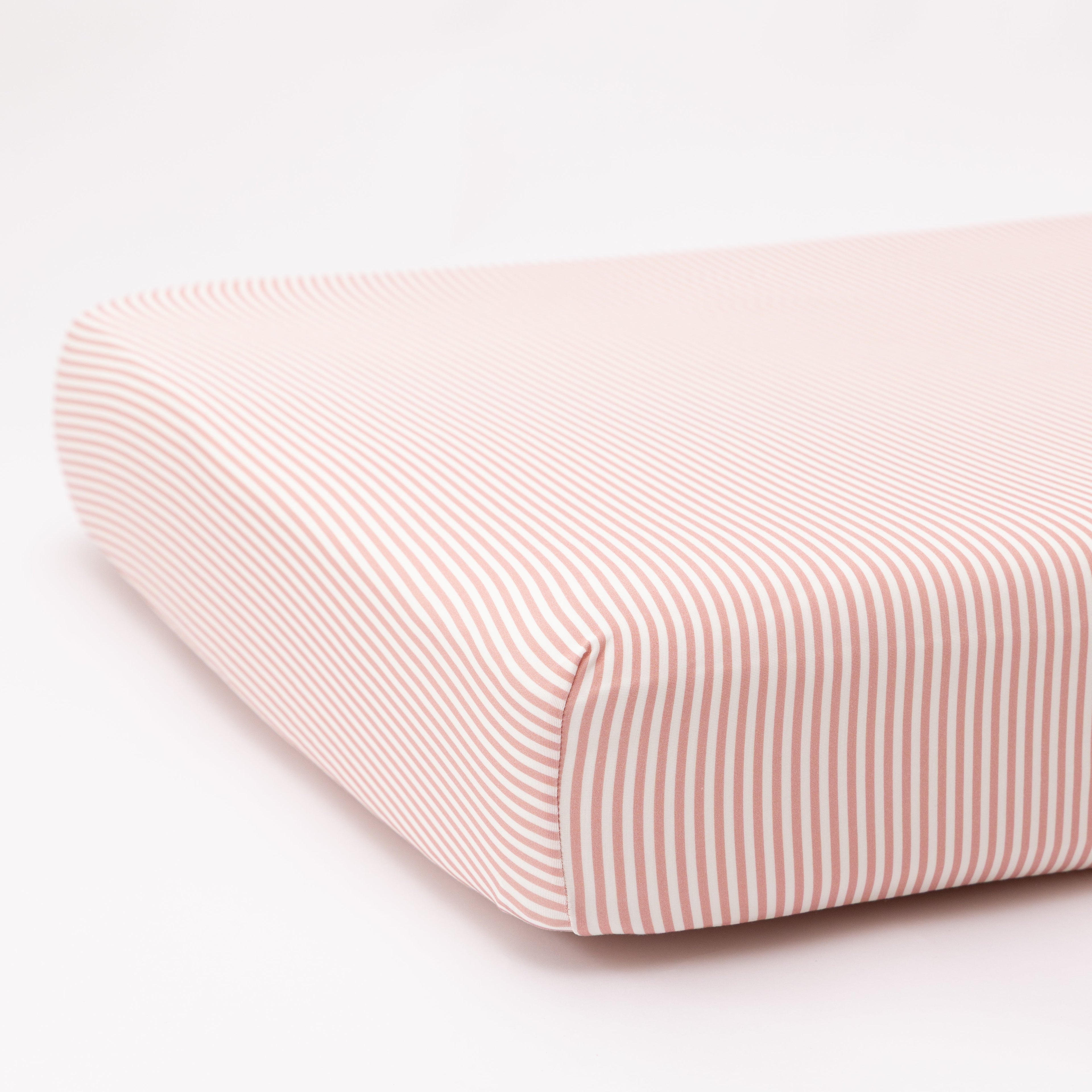 Pink and white striped crib sheet on a white background