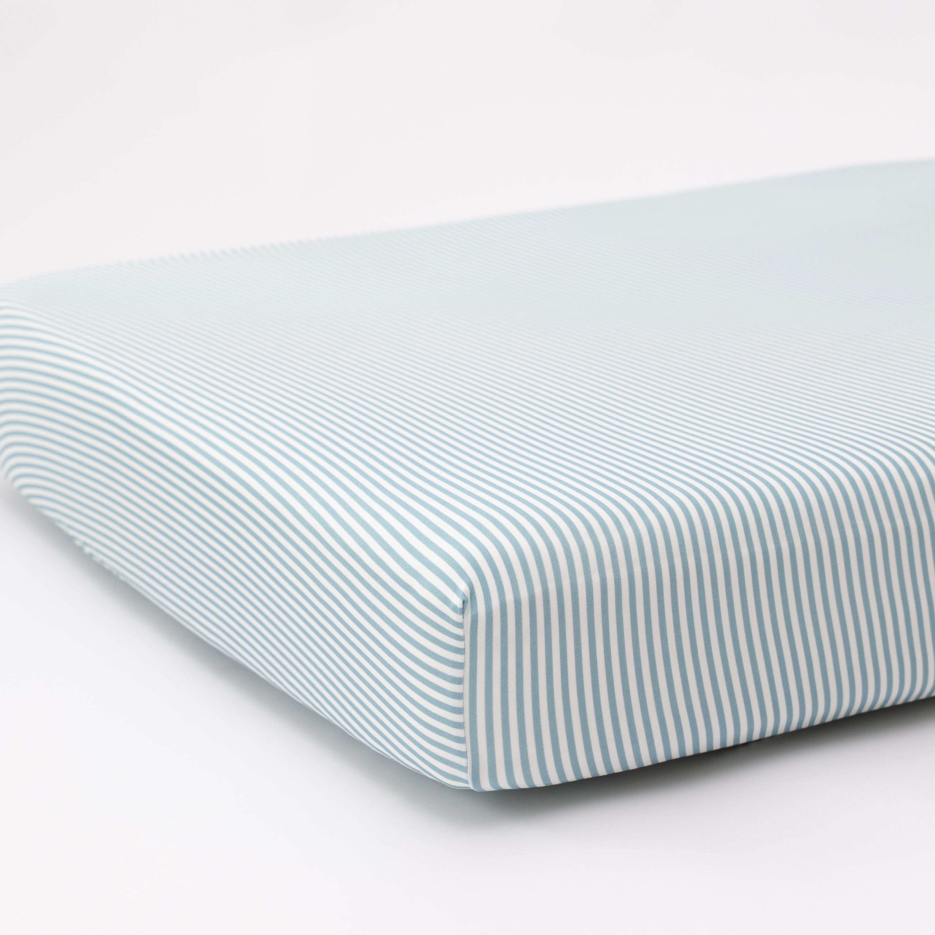 Striped fitted sheet on a mattress with a white background