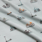 Fabric with small bicycle and scooter patterns on a light blue background