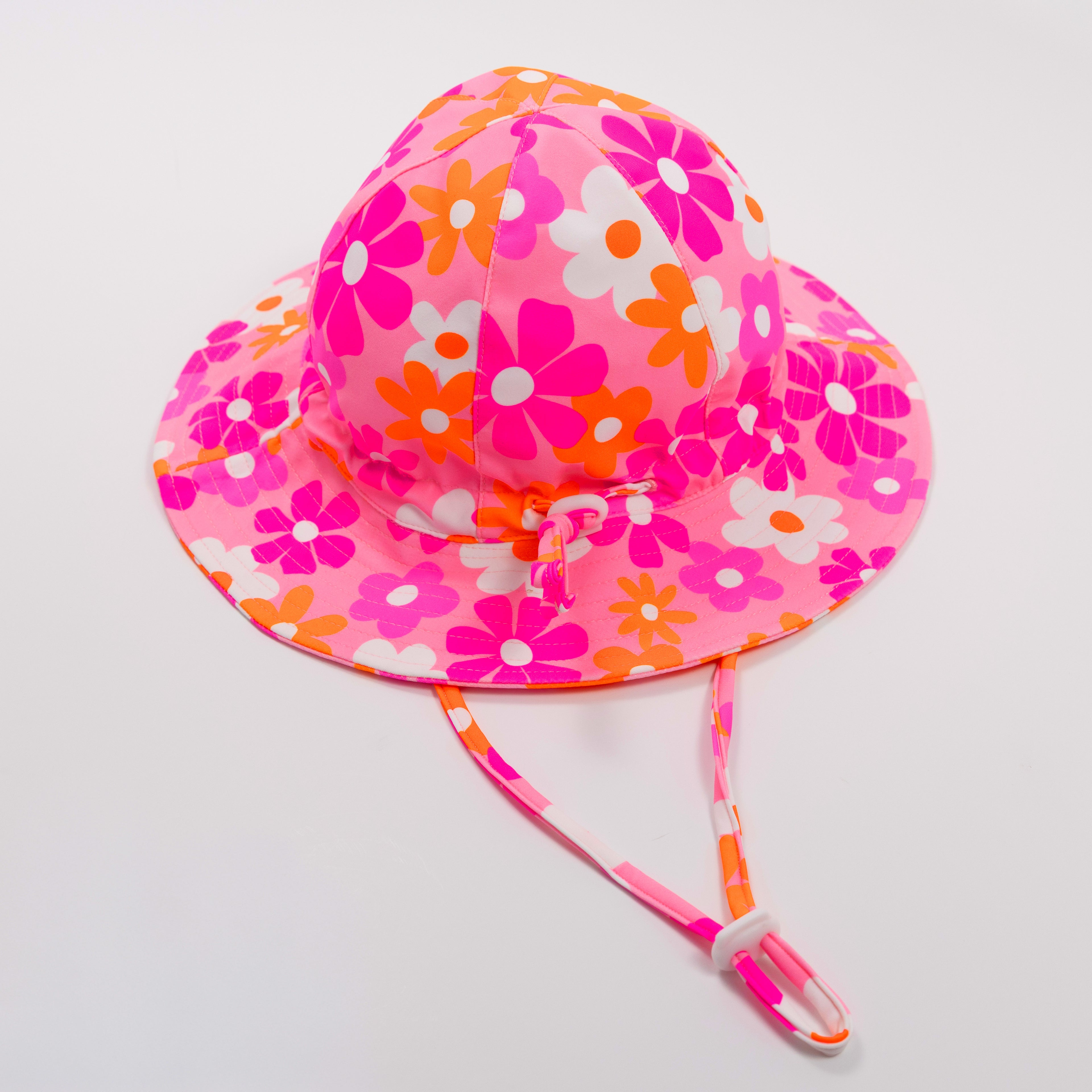 Floral patterned sun hat with a strap on a plain background