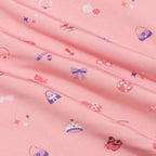 Pink fabric with small colorful patterns including bows and hats.