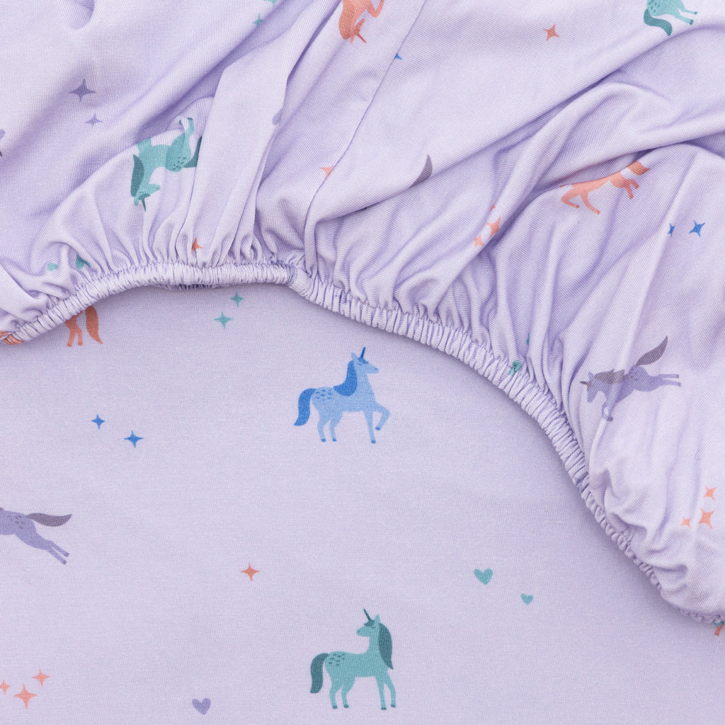 Close up of fabric sheet with colorful unicorn prints on a light purple background