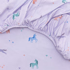 Close up of fabric sheet with colorful unicorn prints on a light purple background