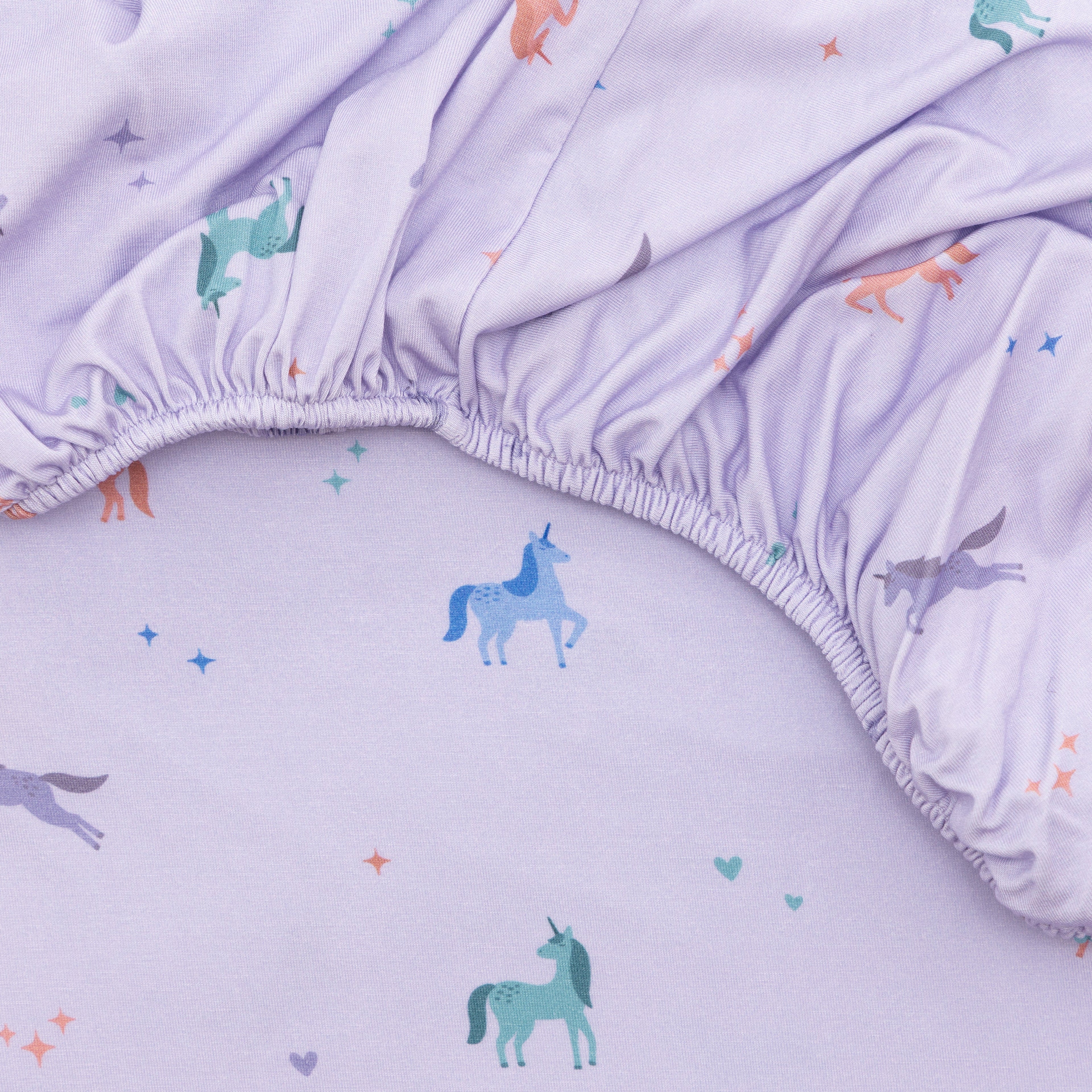 Close up of fabric sheet with colorful unicorn prints on a light purple background
