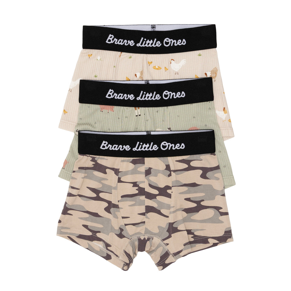 Three pairs of children's underwear with camouflage, farm animals and chickens designs, with 'Brave Little Ones' branding on a white background.