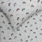 Close up shot of a bed with a vehicle patterned bedding and pillow on a white background