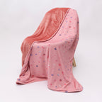 Pink blanket with small girly patterns draped over a chair on a white background