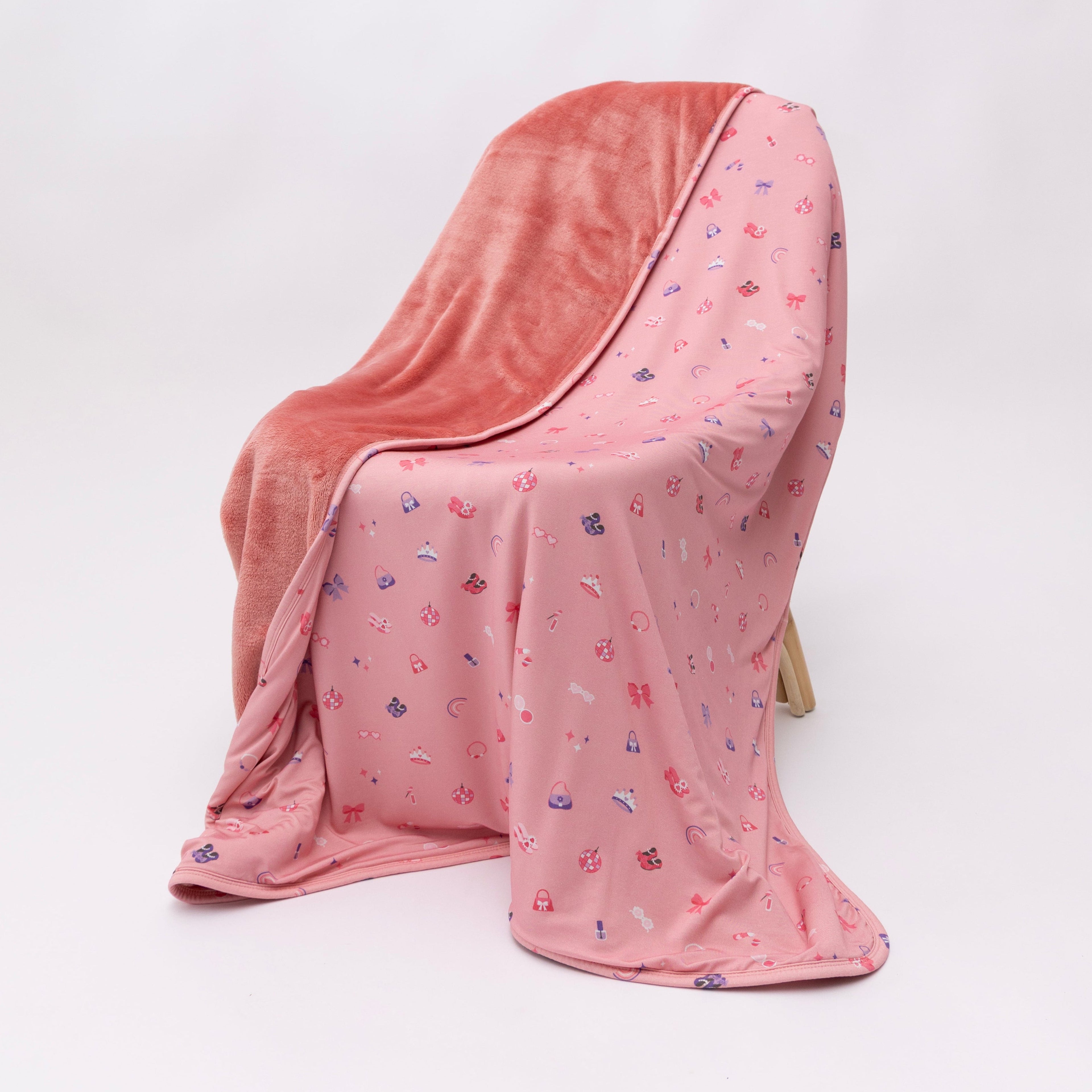 Pink blanket with small girly patterns draped over a chair on a white background