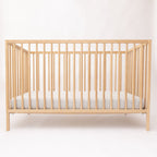 Wooden crib with a gray mattress on a white background
