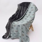 Children's blanket with bicyles & scooters pattern draped on a wooden chair