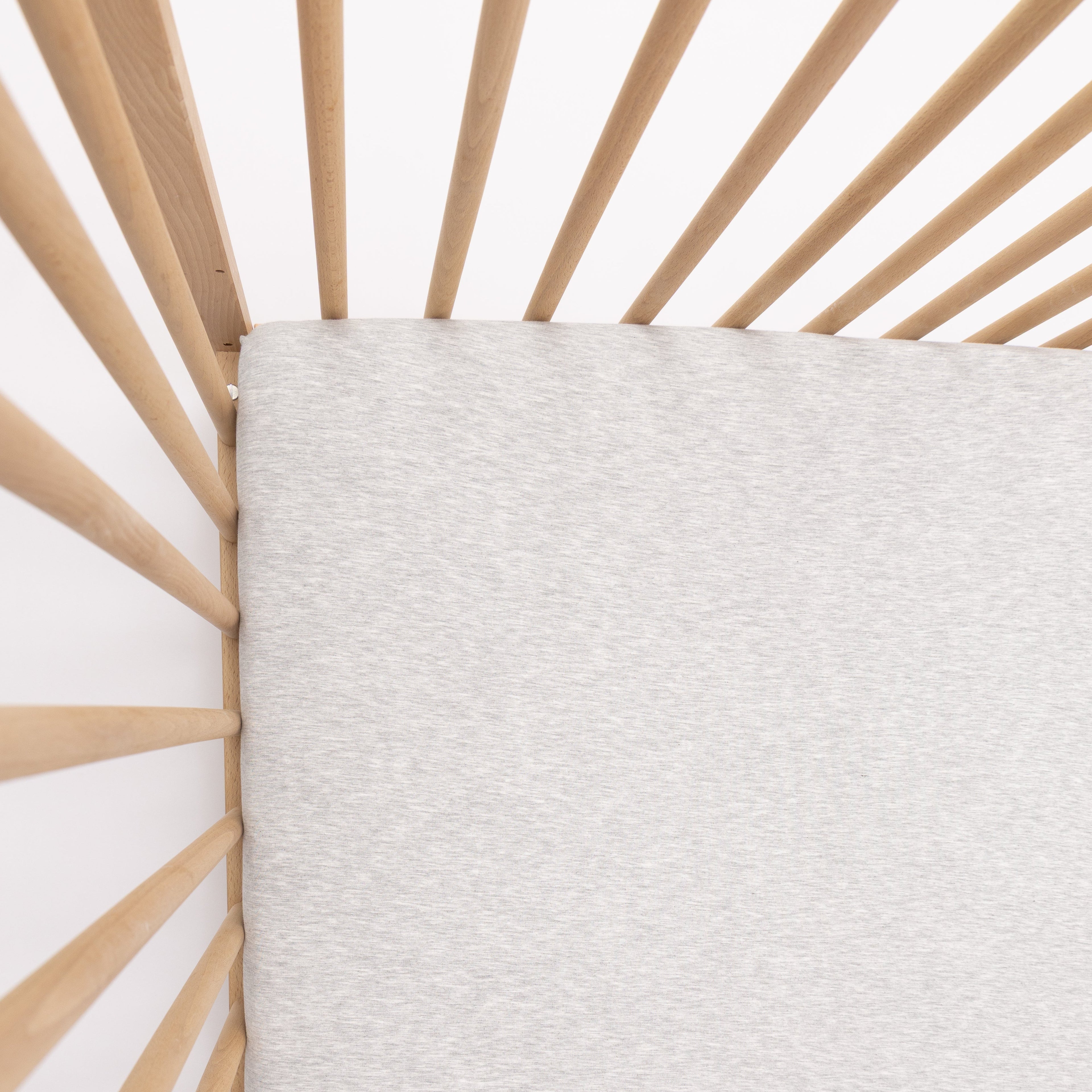 Close-up of a textured gray fabric against a wooden crib frame.
