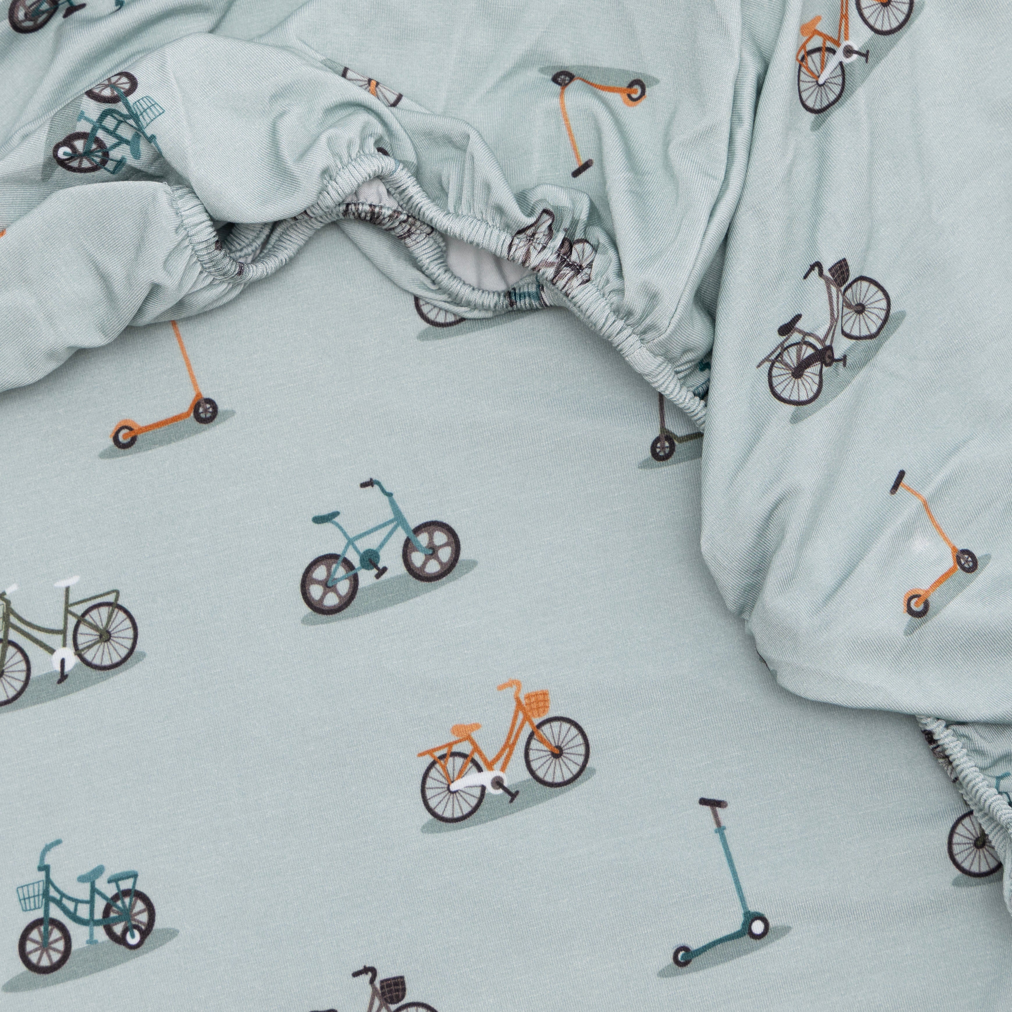 Light blue fabric with bicycle and scooter patterns, with a close-up of a fitted sheet.