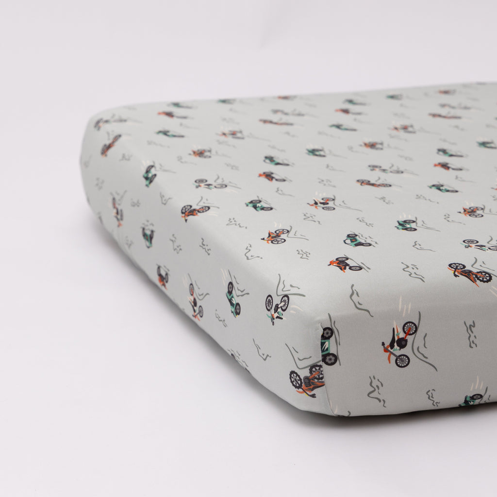 Fitted crib sheet with dirt bike pattern on a white background