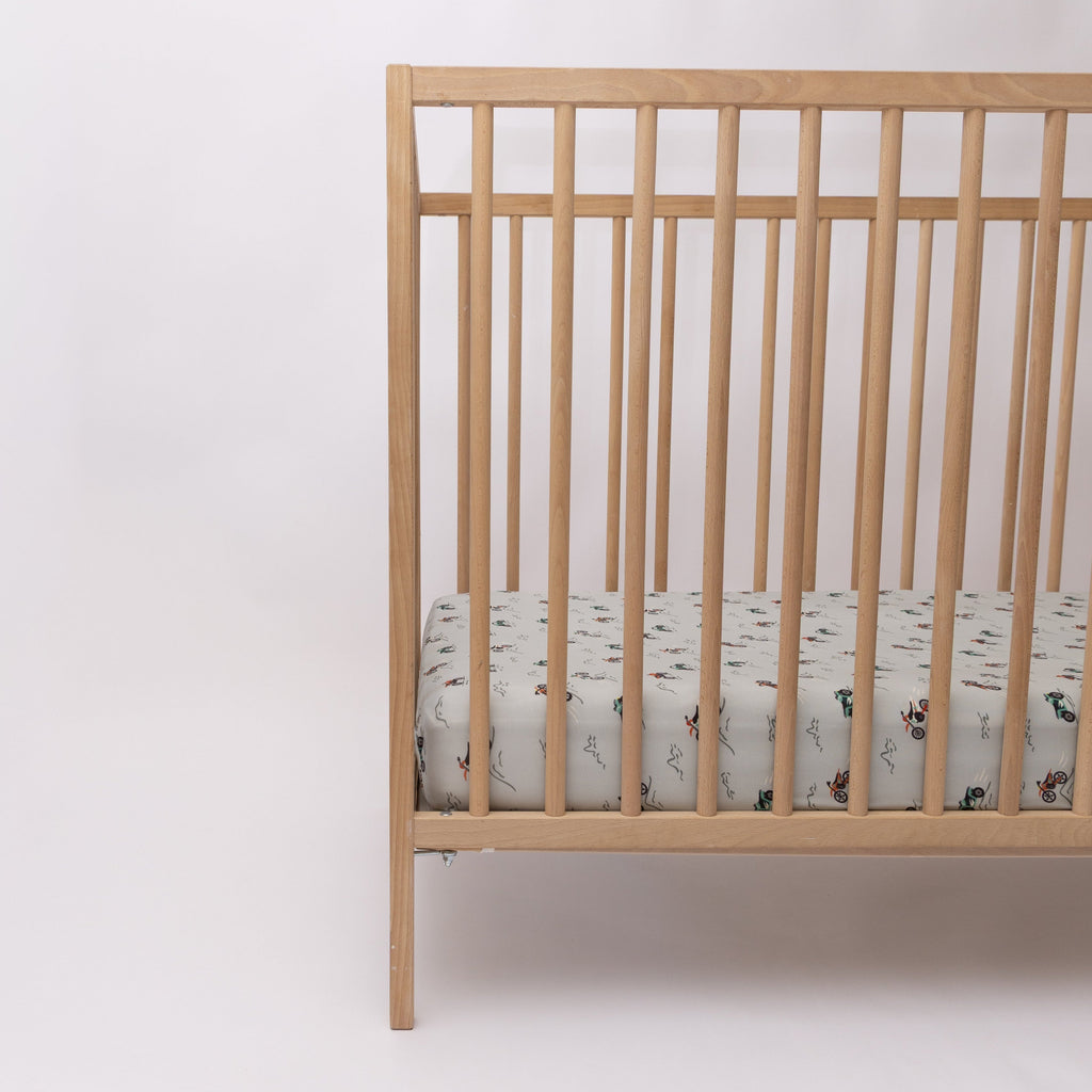 Fitted crib sheet with dirt bike pattern on a wooden crib with mattress