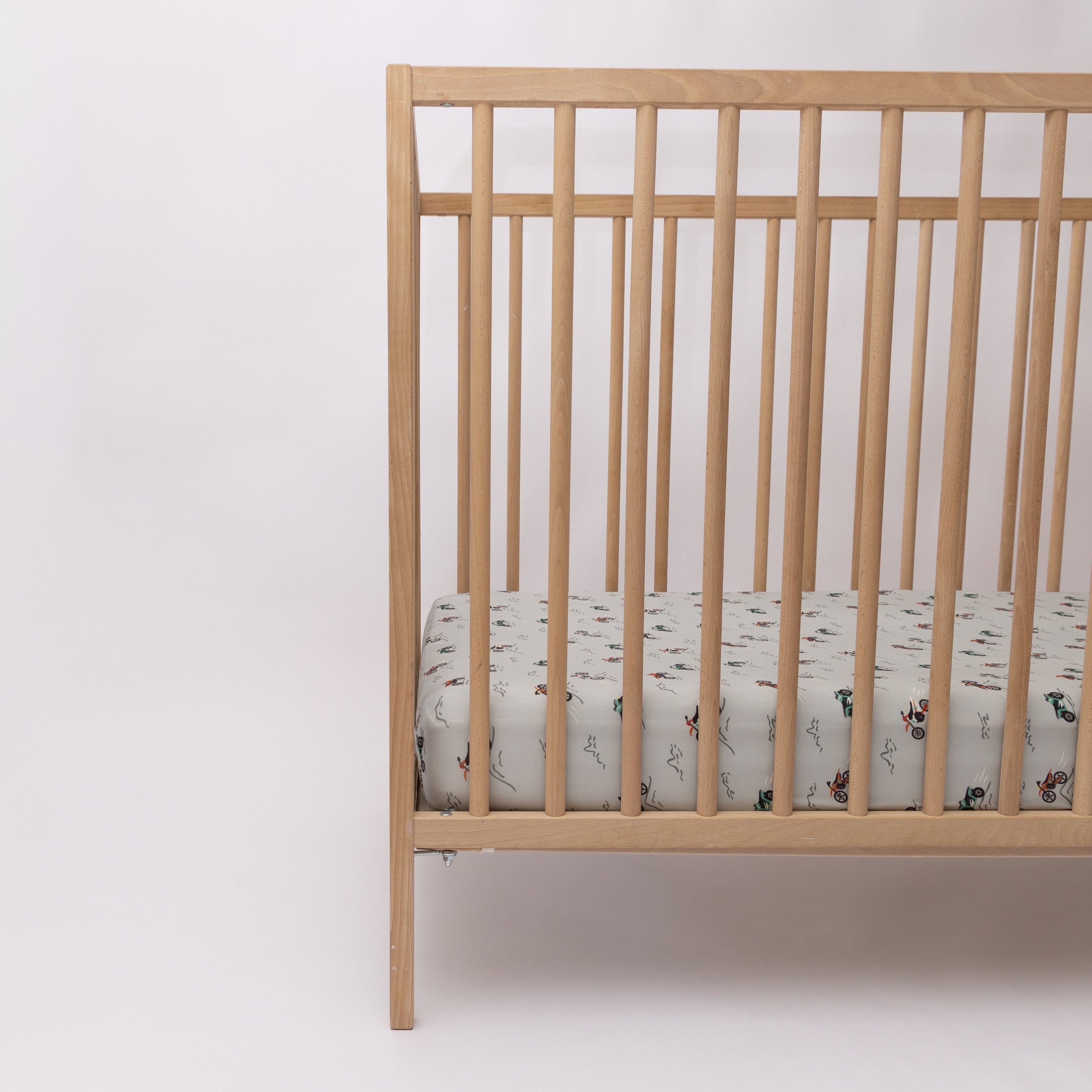 Fitted crib sheet with dirt bike pattern on a wooden crib with mattress