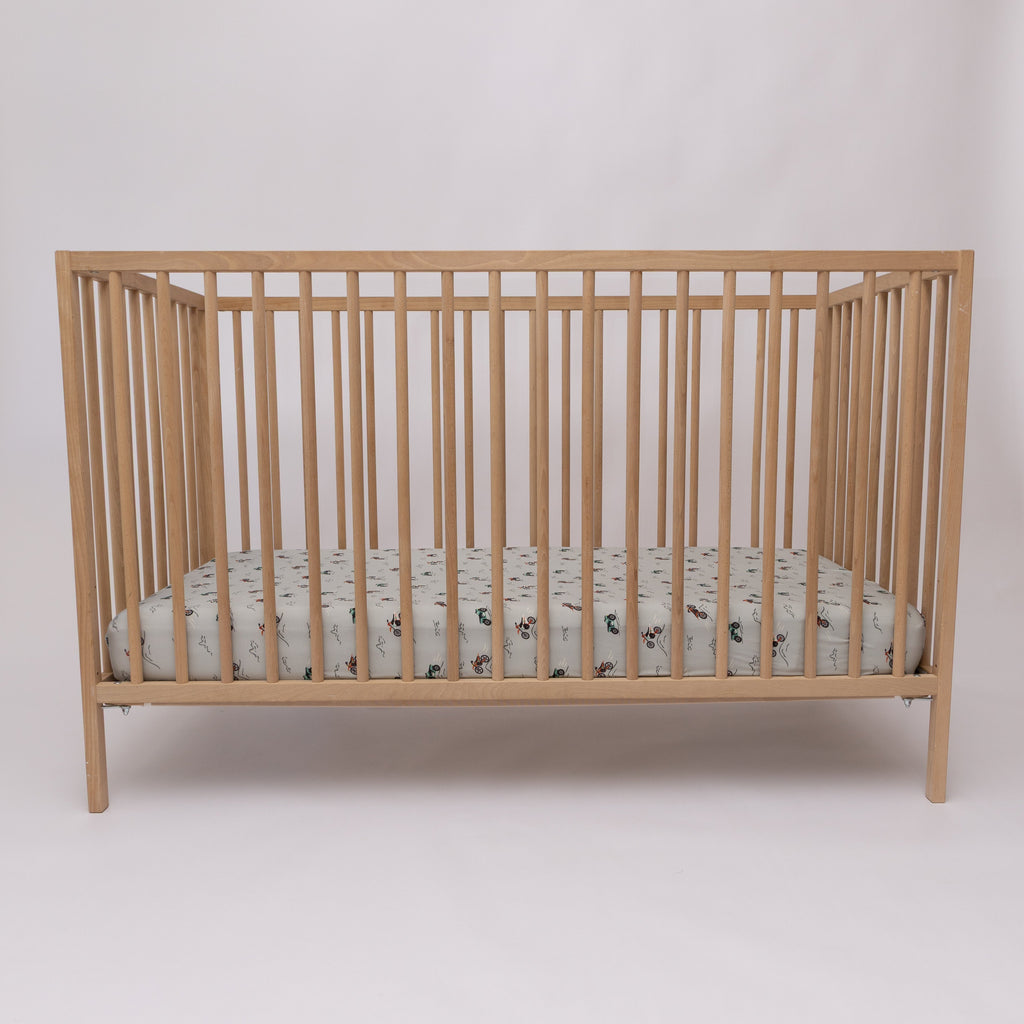 Fitted crib sheet with dirt bike pattern on a wooden crib with mattress
