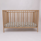 Fitted crib sheet with dirt bike pattern on a wooden crib with mattress