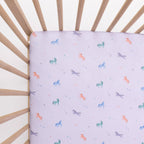 Crib with a fitted sheet featuring colorful unicorn patterns on a light background
