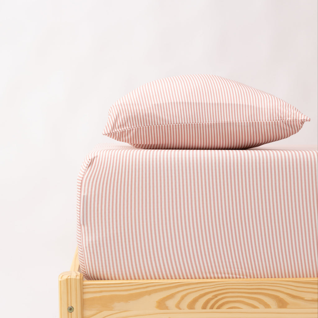 Bed with pink striped bedding and a wooden frame on a white background