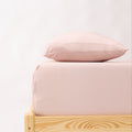 Bed with pink striped bedding and a wooden frame on a white background