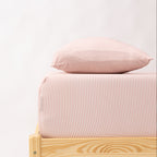 Bed with pink striped bedding and a wooden frame on a white background